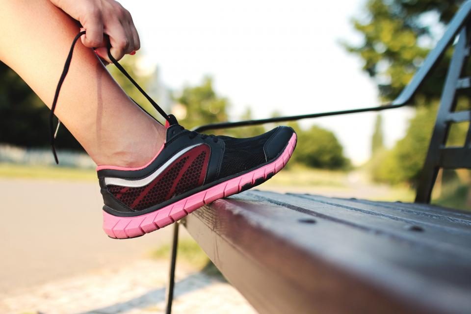 Pessoa amarrando o tênis antes de sair para uma caminhada