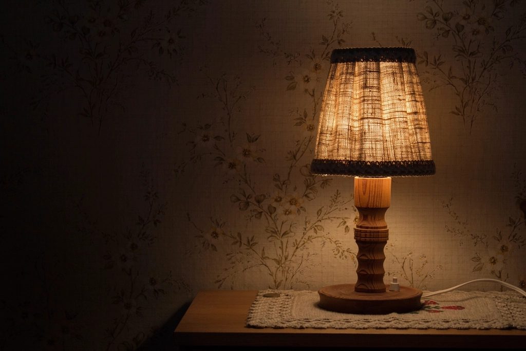 Abajur aceso sobre o criado-mudo em um quarto à noite
