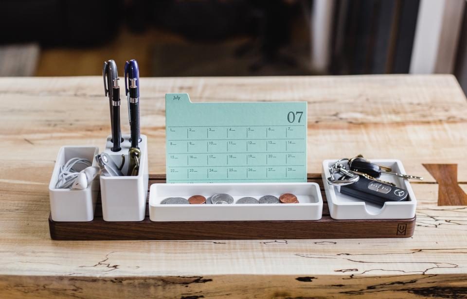Organizador de mesa com canetas e um pequeno calendário sobre a madeira