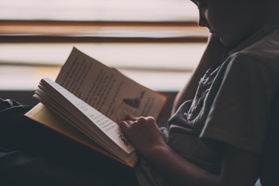 Pessoa lendo e revisando um livro aberto sobre a mesa